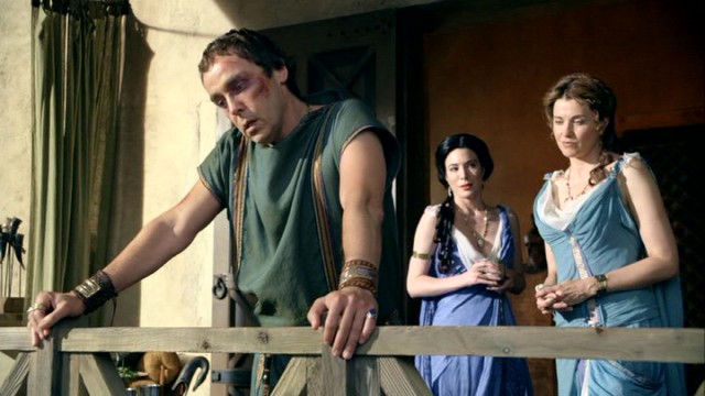 A bruised Quintus Lentulus Batiatus (John Hannah) looks out over his ludus, while Gaia (Jaime Miller) and Lucretia (Lucy Lawless) stand back.