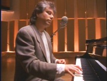 A mulleted Menken performs one of his many famous Disney songs in simpler times.