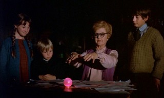 With the children watching, Eglantine tries to cast a spell and succeeds at making the bedknob light up in pink.