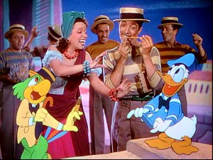Aurora Miranda, Joe Carioca, and Donald Duck dance in "The Three Caballeros", while the mustachioed man makes music with a pencil and his teeth.
