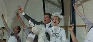 Caractacus (Dick Van Dyke) and Truly (Sally Ann Howes) are excitedly joined by Lord Scrumptious' factory workers in holding up Toot Sweets, the candy you can use as a flute.