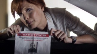 Detective Inspector Anna Travis (Kelly Reilly) holds up a print-out on one of the FBI's Ten Most Wanted criminals.