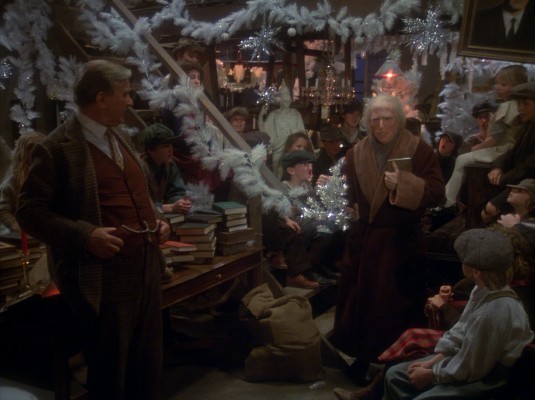 The Ghost of Christmas Present (Gerard Parkes) brings Benedict Slade (Henry Winkler) to an orphanage decorated with white garland.