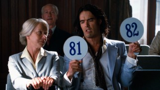 An intoxicated Arthur (Russell Brand) amuses himself (but not Helen Mirren) with an auction bidding war with himself.