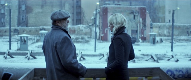 Lorraine Broughton (Charlize Theron) meets with American CIA agent Emmett Kurzfeld (a white bearded John Goodman) by the Berlin Wall.