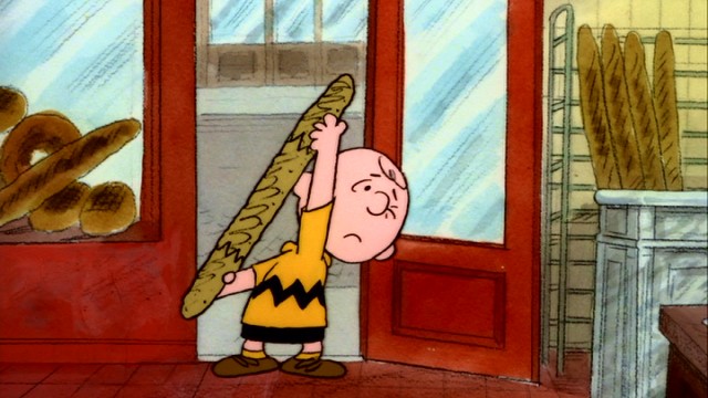 International blockhead: Charlie Brown struggles to get a baguette through a French bakery's door.