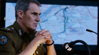 Unable to get ahold of anyone with greater authority, Deputy Inspector General Morris Da Silva (Ben Cross) is in charge of the official response to the bomb threats.