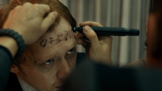 Rupert Grint has a phone number written on his forehead in marker in the thankless comic relief supporting role of Karl.