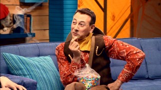 A cowboy-costumed Pee-Wee Herman savors a single piece of his all-chocolate trail mix in the Halloween episode.