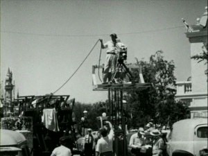 A cameraman stands on an elevated platform to capture Disneyland's opening day in the dry how-we-did-it piece "Operation Disneyland."