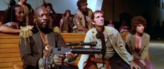 Remaining in question throughout the film is the loyalty of "Brain" (Harry Dean Stanton, center) and his chesty girlfriend Maggie (Adrienne Barbeau) to A-Number-1 prisoner The Duke (Isaac Hayes).