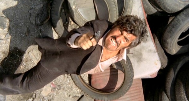 Luca Canali (Mario Adorf) shoots up at a heap in the memorable junkyard shootout that concludes "The Italian Connection."