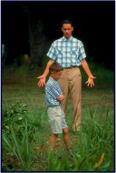 This photo gallery still shows us young (Michael Conner Humphries) and adult (Tom Hanks) Forrest Gumps interacting in their characteristic blue and white checkered shirts.