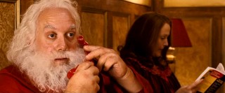 In bed with his wife Annette (Miranda Richardson), fat-fingered Santa Claus (Paul Giamatti) gets a jail call from his brother.
