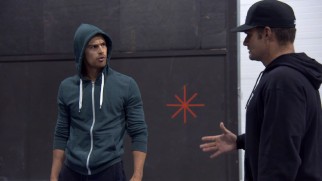 Theo James endures his physical training in a gray hooded sweatshirt.