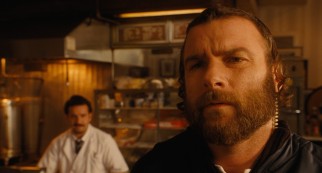 Hasidic police officer Dovi (Liev Schreiber) grows suspicious of Murray, while Max Casella works a counter in the background.