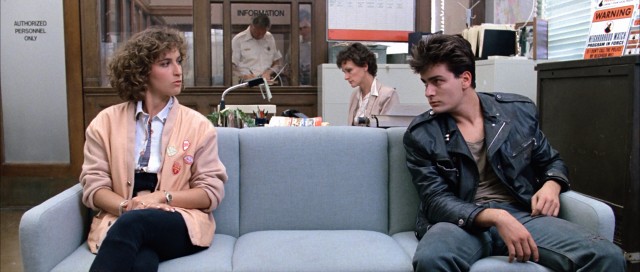 At the Shermer Police Station, Jeanie Bueller (Jennifer Grey) makes the acquaintance of a tired-looking young man (Charlie Sheen).