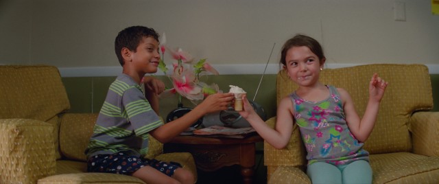 Scooty (Christopher Rivera) and Moonee (Brooklynn Kimberly Prince) eat an ice cream cone bought for them by tourists inside the Magic Castle motel in "The Florida Project."