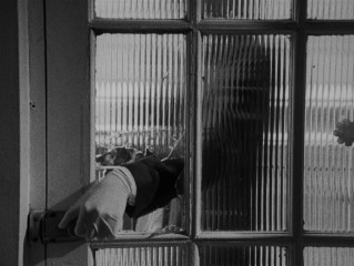 A latex gloved hand breaks and enters through a door's glass pane.