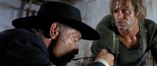 Klaus Kinski plays hunchbacked bandit Juan Wild, seen here interrupting Mortimer's meal to settle a score.