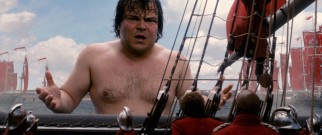 A wet, shirtless Gulliver (Jack Black) encourages the Blefuscian Armada to retreat in response to his antics.