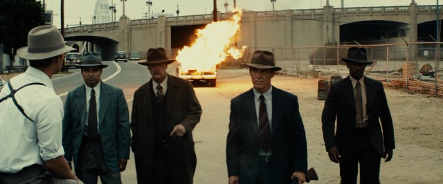 The Gangster Squad walks calmly and coolly away from an exploded car.