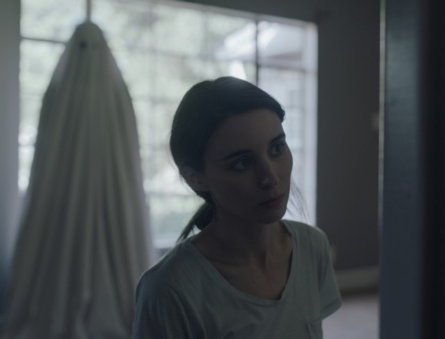 The ghost (Casey Affleck) looks on as his widow (Rooney Mara) grieves in the house they shared.