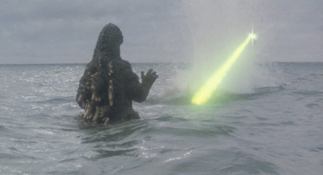 Godzilla makes an aquatic return from Mt. Mihara and is greeted by the green light of military aircraft fire.