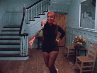 The always head-scarved, apparently patriotic Little Edie waves a flag and dances in "Grey Gardens."