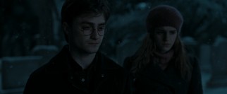 On a snowy Christmas Eve in Godric's Hollow, Harry (Daniel Radcliffe) and Hermione (Emma Watson) pay respects at Harry's parents' grave.