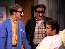 A hospitalized Fonzie doesn't look cheered up by his friends' humorous facewear.