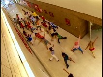 The cast rehearses "What Time Is It?" on the set as we view from the ceiling.