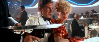 "Temple of Doom", the first sequel/prequel, opens with a life-and-death test of wits, as Indiana Jones (Harrison Ford) holds Shanghai lounge singer Willie Scott (Kate Capshaw) hostage with a gun-toting "waiter" on his side.