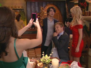 Joe (Joe Jonas) and Stella (Chelsea Staub) attempt to skewer each other at dinner, but not before Macy has them freeze with Van Dyke (Chuck Hittinger) for a photo op.