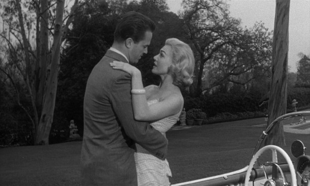 For no apparent reason, hardboiled "bedroom dick" Mike Hammer (Ralph Meeker) gets a warm, friendly greeting from easy Friday (Marian Carr) at a gathering he wasn't invited to.