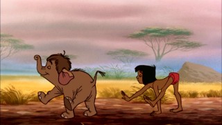 Mowgli imitates the elephant Junior. Despite his wild upbringing, he is still a man cub, not a pachyderm.