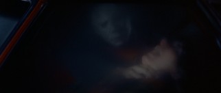 A grown-up, masked Michael Myers strikes in a car.