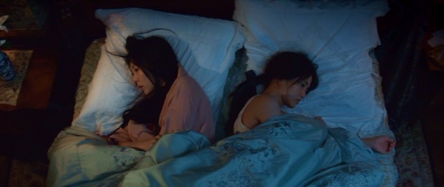 Lady Hikdeo (Kim Min-hee) and her handmaiden Sook-Hee (Kim Tae-ri) are closer than they let in as they share a bed but face opposite directions here.