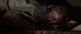 A darkened, stealthy Corporal Allison (Robert Mitchum) stays quiet while a giant rat crawls on his legs.