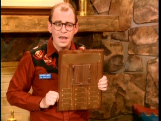 Mr. Ernst (David Brisbin) hopes to motivate his staff with the site of an Employee of the Week plaque.