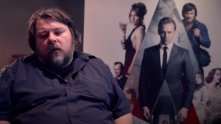 Director Ben Wheatley discusses bringing Ballard to the big screen in front of a "High-Rise" poster.