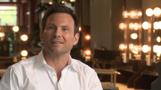 Christian Slater discusses "Choozy Doozy", the top-rated game show of the future his character hosts in his uncredited cameo.