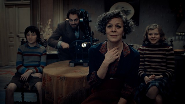 The power of cinema is unleashed as film author Rene Tabard (Michael Stuhlbarg) cranks a projector for Hugo, Isabelle, and Mama Jeanne Méliès (Helen McCrory).