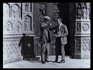 Lon Chaney shows an unidentified man the Notre Dame set and how he'll climb it in this vintage newsreel clip.