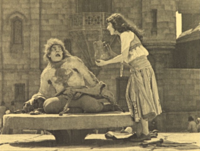 Esmeralda (Patsy Ruth Miller) brings a chained-up Quasimodo (Lon Chaney Sr.) some water in 1923's "The Hunchback of Notre Dame."