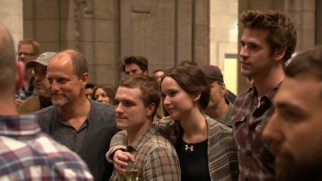 Hunger Games core cast members Woody Harrelson, Josh Hutcherson, Jennifer Lawrence, and Liam Hemsworth are all ears during the series' wrap party toasts near the end of "Pawn No More."