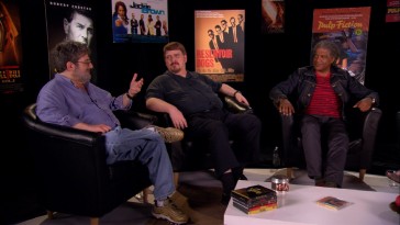 Elvis Mitchell (right) and other film critics break down "Jackie Brown" in front of a semi-circle of Quentin Tarantino movie posters.