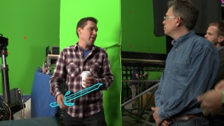 Bryan Singer directs the film on a green screen set with a coffee cup in one hand and an animated sword in the other.