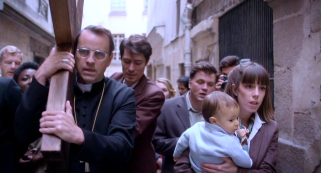 Cardinal Lustiger (Laurent Lucas) carries a cross like Jesus as believers follow him in procession.
