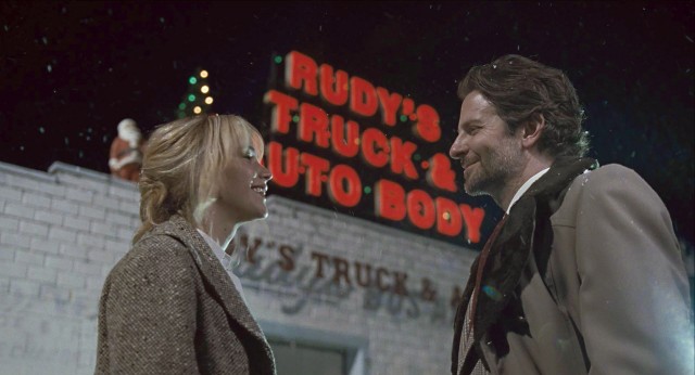 QVC executive Neil Walker (Bradley Cooper) drops in to see Joy (Jennifer Lawrence) at her father's workplace Christmas party.